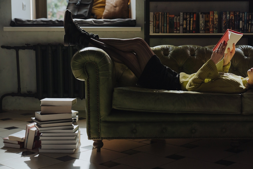 Person lying down on sofa reading a book